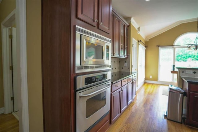 kitchen with tasteful backsplash, light hardwood / wood-style floors, stainless steel appliances, vaulted ceiling, and crown molding