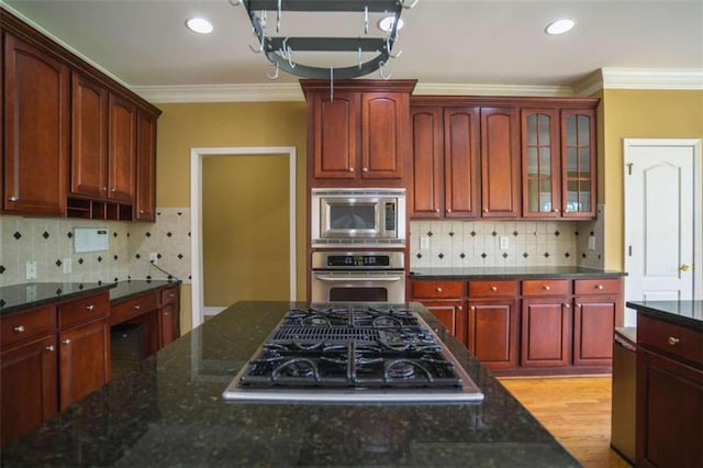 kitchen featuring ornamental molding, decorative backsplash, appliances with stainless steel finishes, and dark stone counters