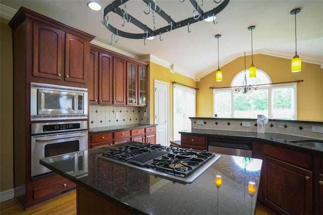 kitchen with backsplash, light hardwood / wood-style flooring, dark stone countertops, stainless steel appliances, and decorative light fixtures