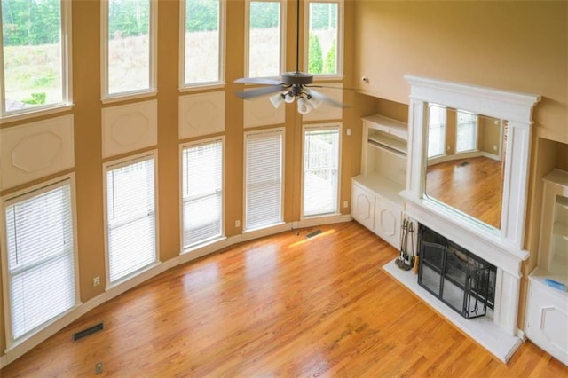 unfurnished living room with a wealth of natural light, a high ceiling, light hardwood / wood-style flooring, and ceiling fan