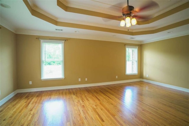 unfurnished room featuring light hardwood / wood-style flooring, ornamental molding, a healthy amount of sunlight, and a raised ceiling