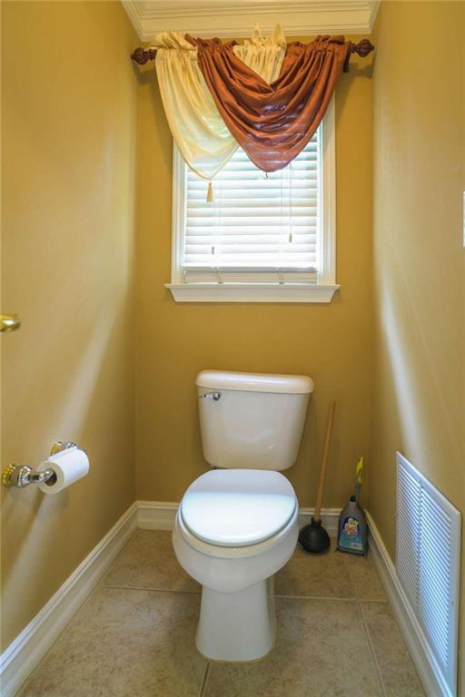 bathroom with ornamental molding, toilet, and tile patterned flooring