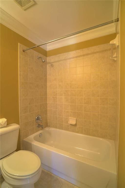 bathroom with toilet, crown molding, tiled shower / bath combo, and tile patterned floors