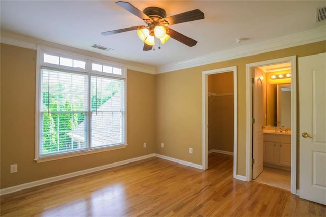 unfurnished bedroom with a spacious closet, multiple windows, and light hardwood / wood-style floors