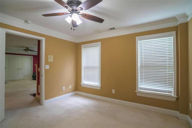 spare room featuring ornamental molding, ceiling fan, light carpet, and plenty of natural light