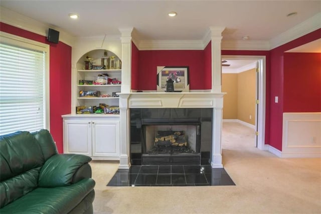 carpeted living room featuring a tiled fireplace, built in features, and ornamental molding