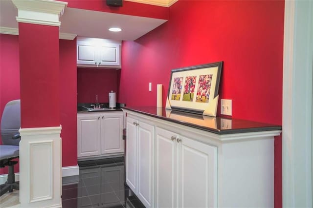 kitchen with dark tile patterned flooring, ornamental molding, sink, and white cabinets