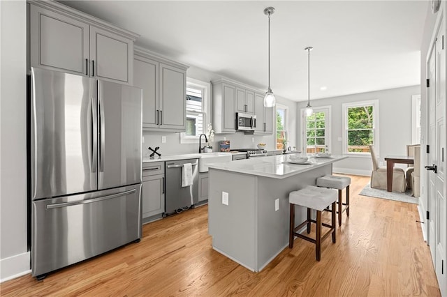 106 Hogue St, Atlanta, GA 30312 - kitchen featuring stainless steel appliances, gray cabinets, light wood finished floors, a kitchen breakfast bar, and a kitchen island