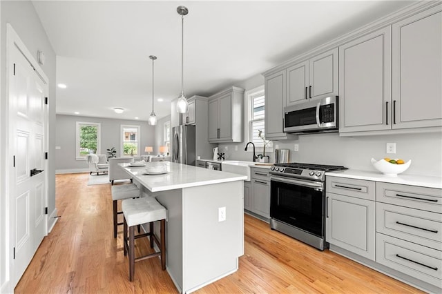 106 Hogue St, Atlanta, GA 30312 - kitchen featuring appliances with stainless steel finishes, gray cabinetry, a sink, a center island, and a kitchen breakfast bar