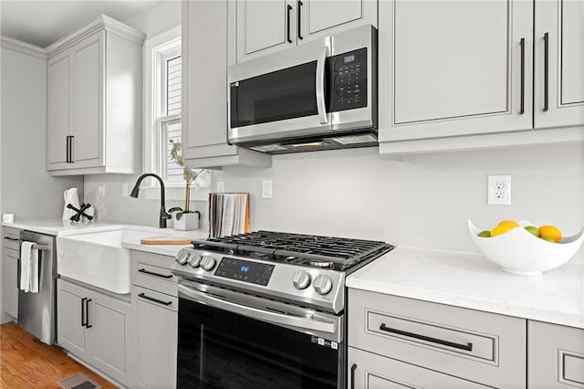 106 Hogue St, Atlanta, GA 30312 - kitchen with appliances with stainless steel finishes, a sink, light wood-style flooring, and light stone countertops