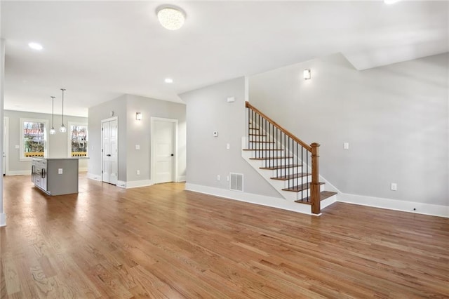 106 Hogue St, Atlanta, GA 30312 - unfurnished living room with light wood finished floors, baseboards, stairway, and recessed lighting