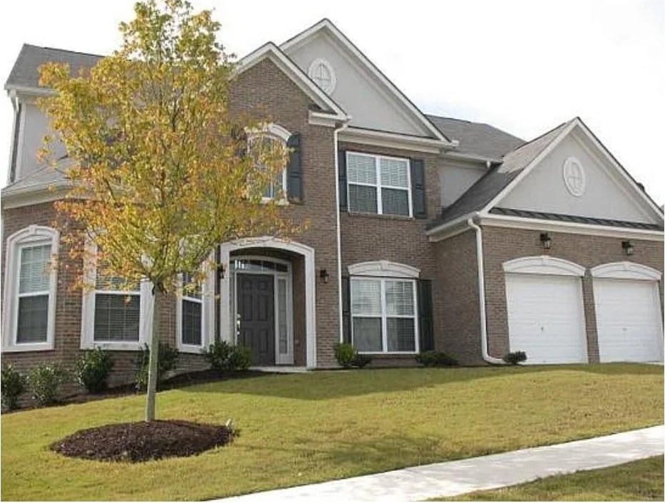 view of front of house with a front lawn, brick siding, and a garage