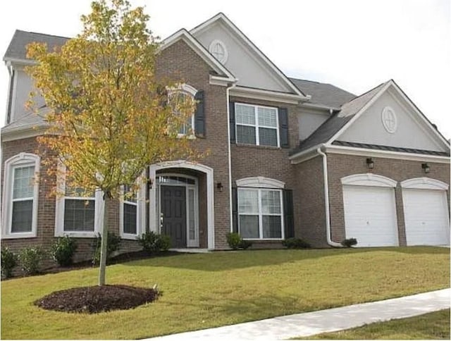 view of front of house with a front lawn, brick siding, and a garage