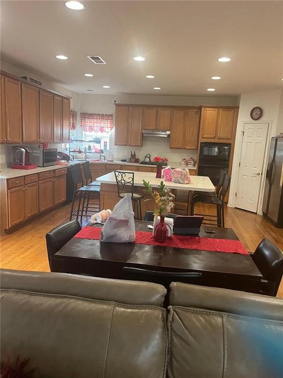 947 Simonton View Ln, Lawrenceville, GA 30045 - kitchen featuring appliances with stainless steel finishes, light wood-style flooring, brown cabinets, recessed lighting, and light countertops