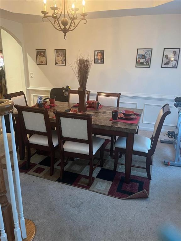 947 Simonton View Ln, Lawrenceville, GA 30045 - carpeted dining space with arched walkways, a wainscoted wall, a chandelier, and a decorative wall