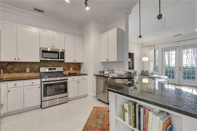 kitchen featuring visible vents, a sink, stainless steel appliances, dark countertops, and tasteful backsplash