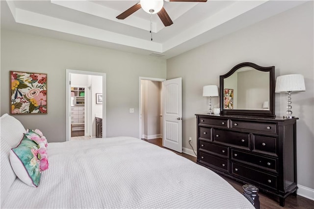 297 Cobblestone Trl, Dallas, GA 30132 - bedroom featuring dark wood-type flooring, a tray ceiling, connected bathroom, and a ceiling fan