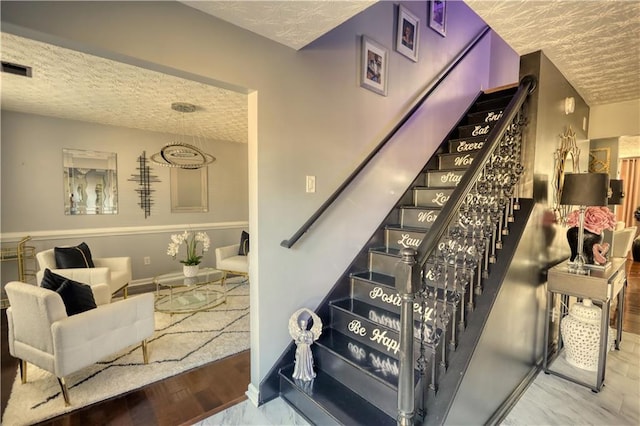 staircase featuring hardwood / wood-style floors and a textured ceiling