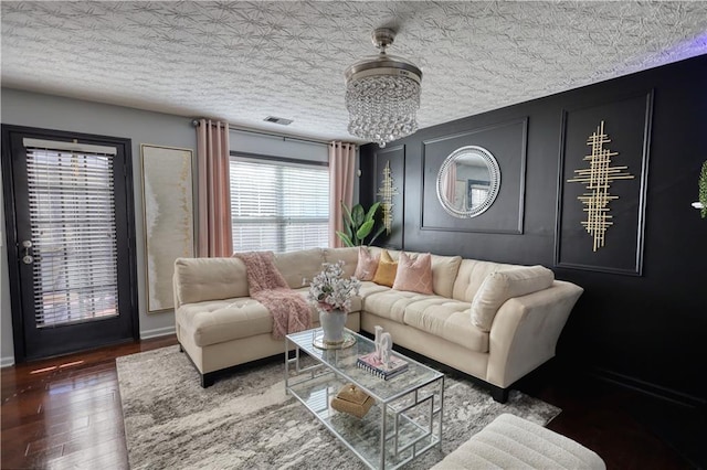 living room featuring dark hardwood / wood-style flooring, a textured ceiling, and a notable chandelier