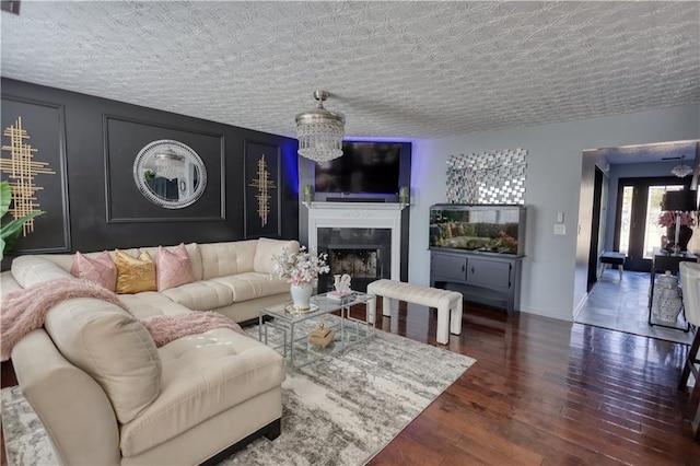 living room featuring an inviting chandelier, a fireplace, dark hardwood / wood-style floors, and a textured ceiling