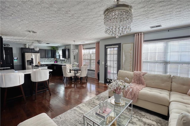 living room with a chandelier, a textured ceiling, and dark hardwood / wood-style flooring