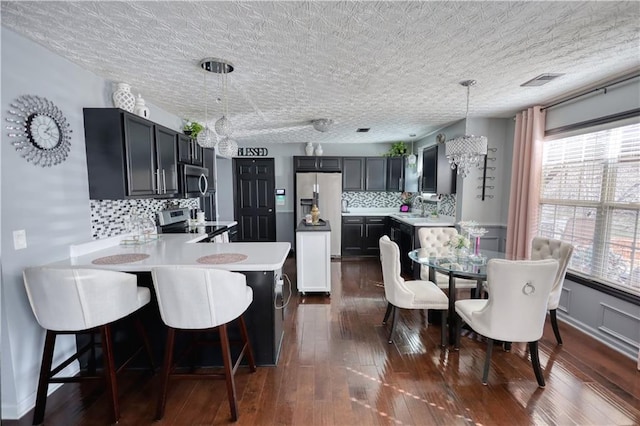 kitchen featuring pendant lighting, sink, appliances with stainless steel finishes, dark hardwood / wood-style floors, and kitchen peninsula