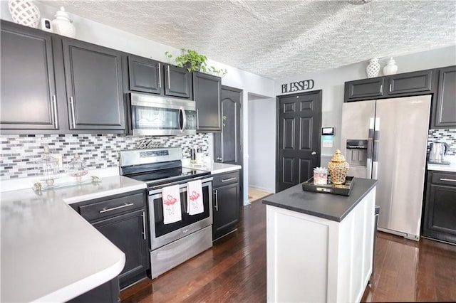 kitchen with appliances with stainless steel finishes, dark hardwood / wood-style floors, decorative backsplash, and a textured ceiling