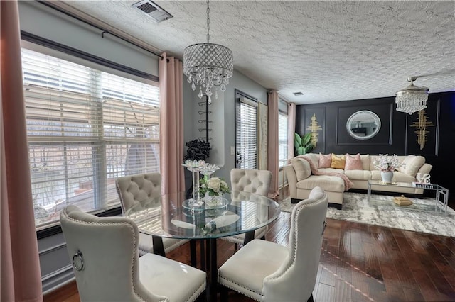 dining area featuring hardwood / wood-style flooring, a textured ceiling, and a notable chandelier