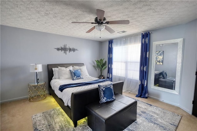 carpeted bedroom featuring ceiling fan and a textured ceiling