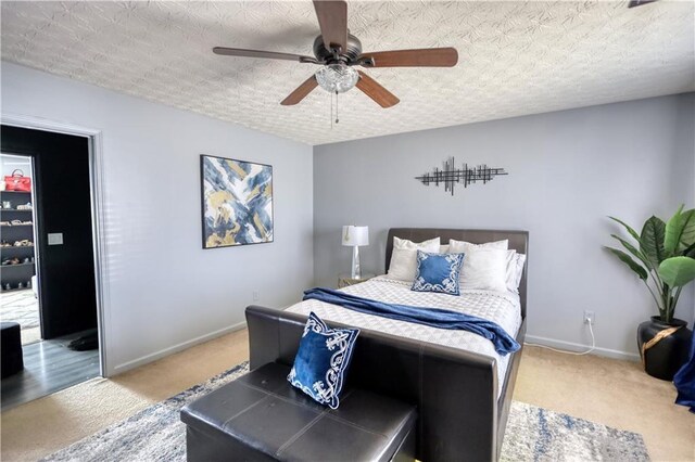 carpeted bedroom featuring ceiling fan and a textured ceiling