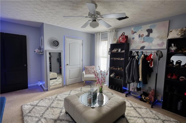 interior space with ceiling fan, light colored carpet, and a textured ceiling