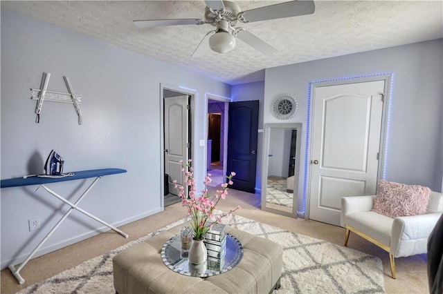 living area with ceiling fan, a textured ceiling, and carpet