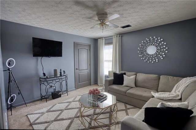 carpeted living room with ceiling fan and a textured ceiling