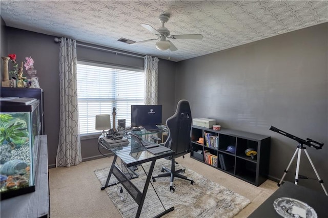 home office featuring ceiling fan, light colored carpet, and a textured ceiling