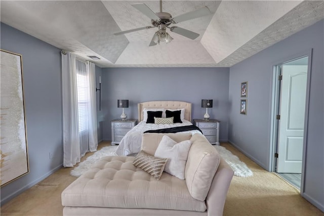 carpeted bedroom with ceiling fan, a tray ceiling, and a textured ceiling