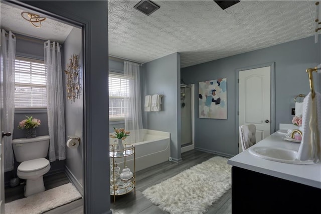 bathroom with hardwood / wood-style floors, vanity, a washtub, toilet, and a textured ceiling