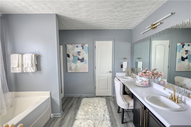 bathroom featuring hardwood / wood-style flooring, vanity, a bath, and a textured ceiling