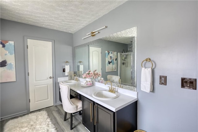 bathroom featuring hardwood / wood-style flooring, vanity, a textured ceiling, and walk in shower