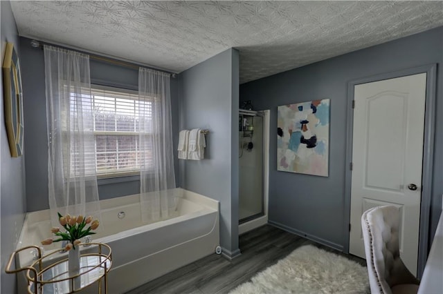 bathroom with wood-type flooring, plus walk in shower, and a textured ceiling