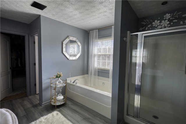 bathroom with hardwood / wood-style flooring, a textured ceiling, and separate shower and tub