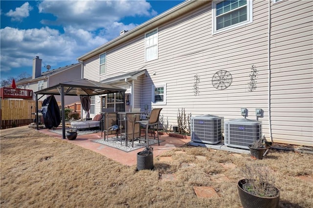 rear view of house with a gazebo, a patio, cooling unit, and a lawn