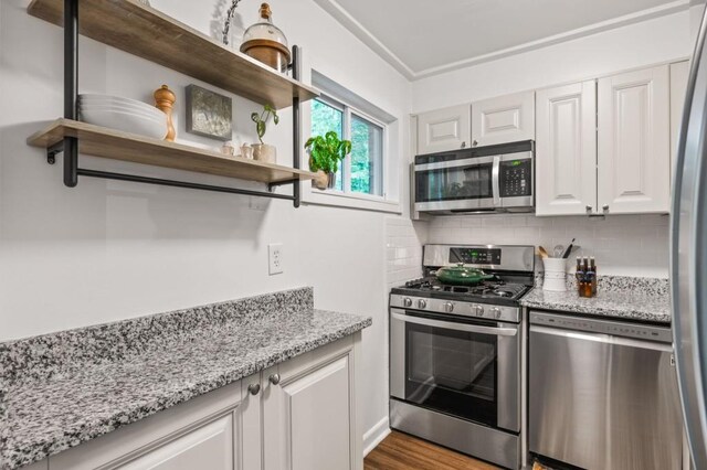 kitchen featuring stainless steel appliances, decorative backsplash, open shelves, white cabinets, and light stone counters