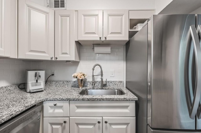 kitchen featuring appliances with stainless steel finishes, a sink, white cabinets, and tasteful backsplash