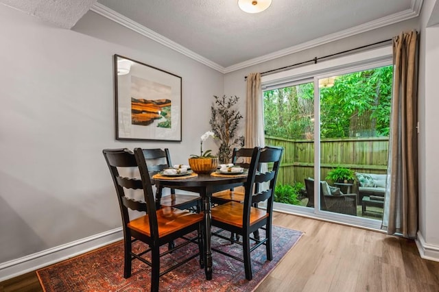 dining space with wood finished floors, crown molding, baseboards, and a textured ceiling