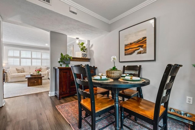 dining space featuring dark wood finished floors and ornamental molding