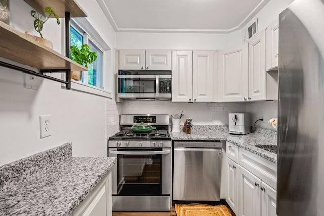 kitchen with appliances with stainless steel finishes, white cabinetry, and tasteful backsplash