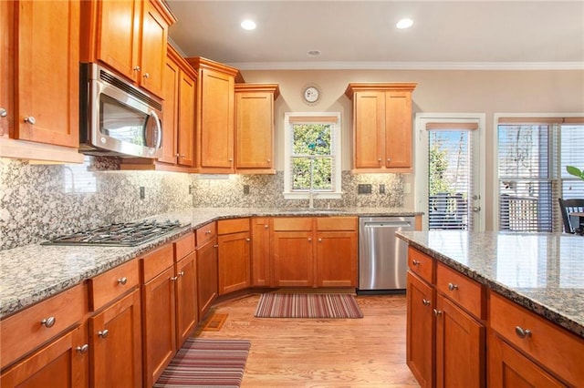 kitchen featuring appliances with stainless steel finishes, crown molding, a sink, and backsplash