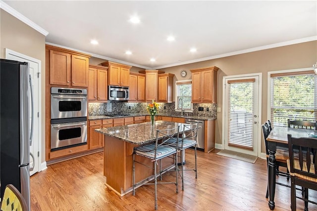 kitchen featuring decorative backsplash, light wood-style flooring, a breakfast bar, a center island, and stainless steel appliances