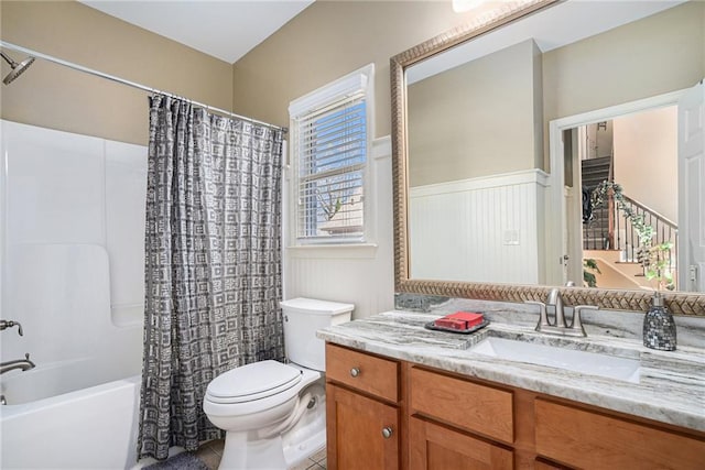 bathroom featuring shower / bath combo, toilet, a wainscoted wall, tile patterned floors, and vanity