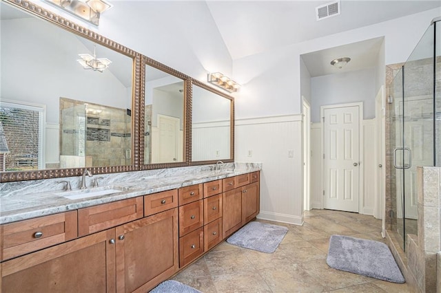 bathroom featuring lofted ceiling, visible vents, wainscoting, a sink, and a shower stall